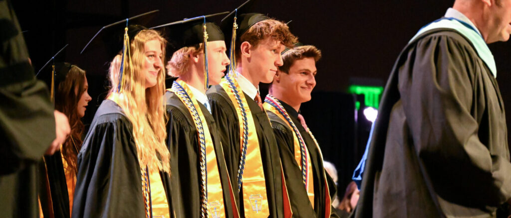 senior student in cap and gown at college prep school graduation